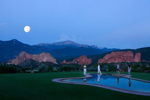 a group of people standing around a pool with mountains in the background at Garden of the Gods Resort & Club in Colorado Springs