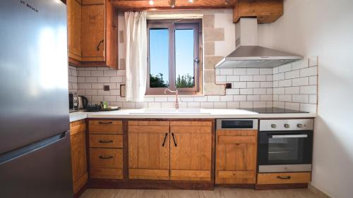 a kitchen with wooden cabinets and a sink and a window at Estia in Plátanos