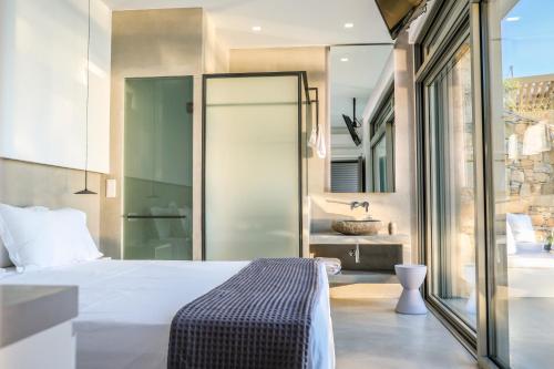 a bedroom with a bed and a bathroom with a sink at Thalasses Villas Skiathos in Skiathos Town