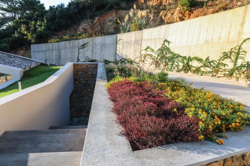 a garden with flowers and a retaining wall at Thalasses Villas Skiathos in Skiathos Town