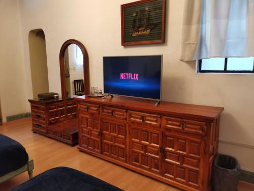 a living room with a tv on a wooden entertainment center at Home Sweet Home in Cuernavaca
