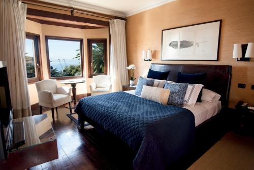 a bedroom with a bed with a blue comforter at Hotel Casa Higueras in Valparaíso