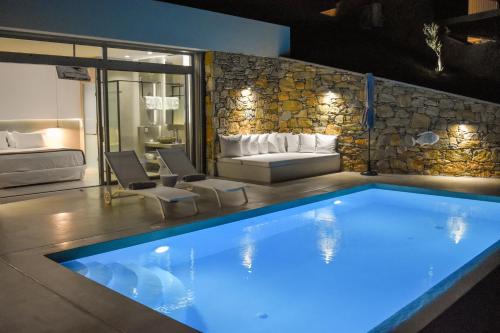 a large swimming pool in a room with a couch at Thalasses Villas Skiathos in Skiathos Town