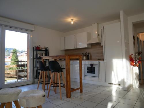 une cuisine avec une table et quelques chaises dans l'établissement Appartement Les Papillons plein centre ville Gerardmer, à Gérardmer