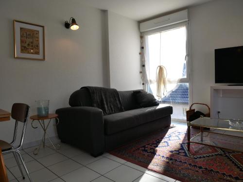 un salon avec un canapé et une fenêtre dans l'établissement Appartement Les Papillons plein centre ville Gerardmer, à Gérardmer