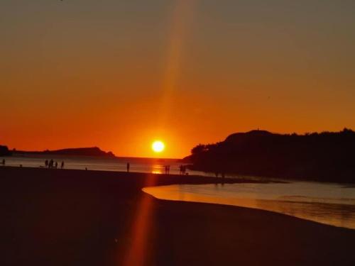 a sunset on a beach with the sun setting at 67 Newquay Getaway in Newquay Bay Resort