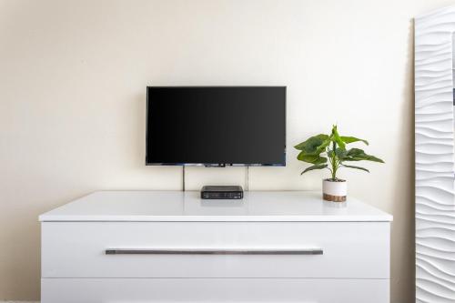 a tv on top of a white dresser with a plant at Sunny Isles Ocean Reserve Condo Apartments in Miami Beach