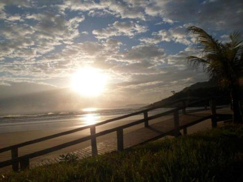a sunset on a beach with a fence and the ocean at Di Raffaele Bombinhas in Bombinhas