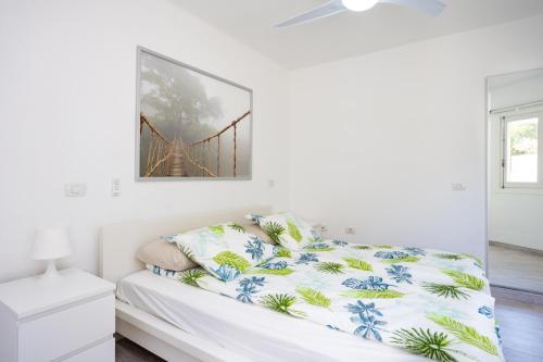 a white bedroom with a bed with a painting on the wall at GIGANTES Oasis Deluxe by Sunkeyrents in Santiago del Teide