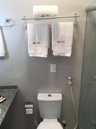 Un baño con inodoro y toallas en un estante. en Apartamento Villa do Porto, a 300 metros do Beach Park, en Aquiraz