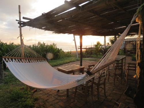 een hangmat op een patio met een tafel en stoelen bij Eco Coco Loco by Rotamundos in Casitas