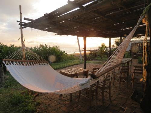 a hammock on a patio with a table and chairs at Eco Coco Loco by Rotamundos in Casitas