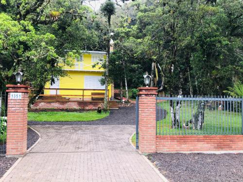 a brick gate with a fence in front of a house at Chalé do Lago in São Francisco de Paula