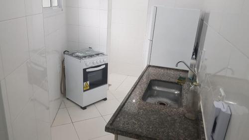 Il comprend une petite cuisine équipée d'un évier et d'une cuisinière. dans l'établissement Apartamento 2 dorm na Guilhermina com tudo novo, Localização Incrível! Internet 200 MB, à Praia Grande