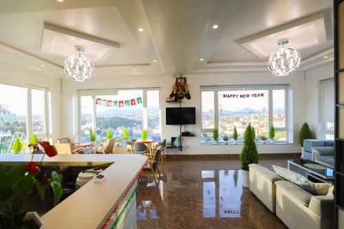 a living room with couches and chairs and windows at Cosy Hotel & Apartment Dalat in Da Lat