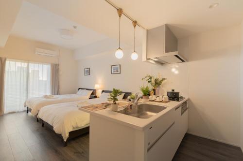 a bedroom with a bed and a sink and a kitchen at 谷町君ホテル WE 難波28 in Osaka