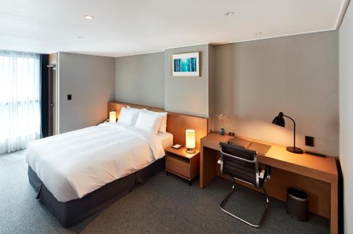 a hotel room with a bed and a desk and a computer at Ramada by Wyndham Gumi in Gumi