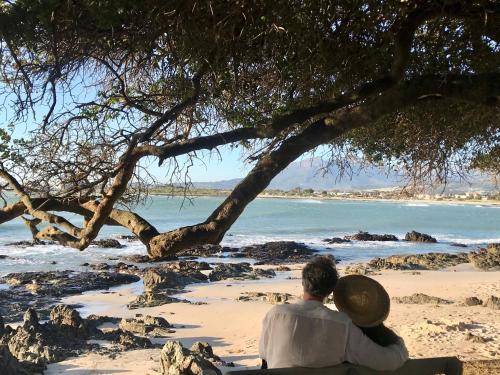 a couple sitting on a bench looking at the beach at Manor on the Bay in Gordonʼs Bay