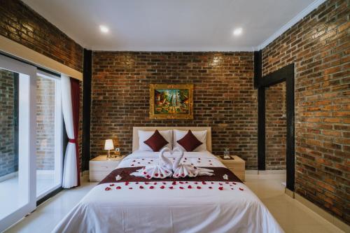 a bedroom with a large bed with a brick wall at Asri Village in Uluwatu