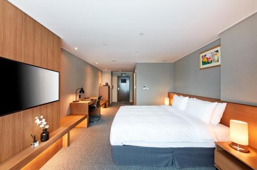 a hotel room with a large bed and a flat screen tv at Ramada by Wyndham Gumi in Gumi