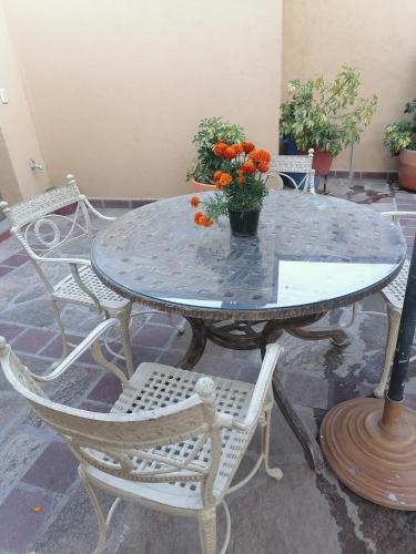 a table with chairs and a vase with orange flowers on it at Posada Las Reynas in Mineral de Pozos