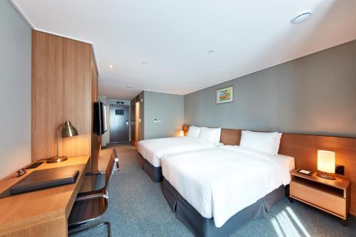 a hotel room with two beds and a television at Ramada by Wyndham Gumi in Gumi