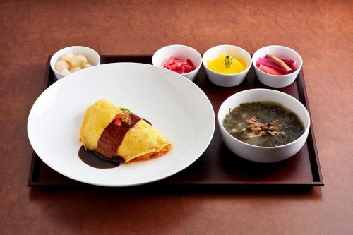 a tray with a plate of food and bowls of soup at Ramada by Wyndham Gumi in Gumi