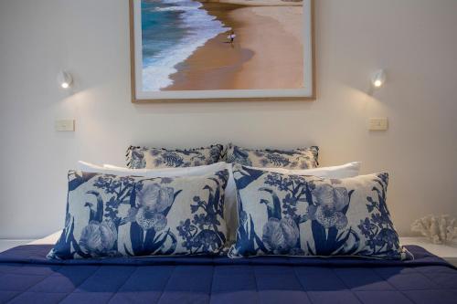 a bedroom with a bed with blue and white pillows at Sea Foam Villas in Port Campbell