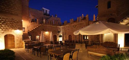 a patio with tables and chairs in a building at night at Kasr-i Nehroz Hotel in Midyat