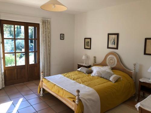 um quarto com uma cama grande e um cobertor amarelo em Le Mas de Fanny em Faucon
