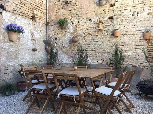 une table et des chaises en bois devant un mur de briques dans l'établissement Maisons de Vignerons, à Noyers-sur-Serein