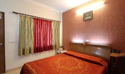 Schlafzimmer mit einem Bett mit roter Bettwäsche und einem Fenster in der Unterkunft Nu Delhi Homestay in Neu-Delhi