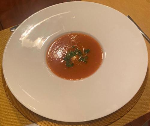 a white plate with a bowl of soup on a table at B&B Villa Anna, Venlo in Venlo