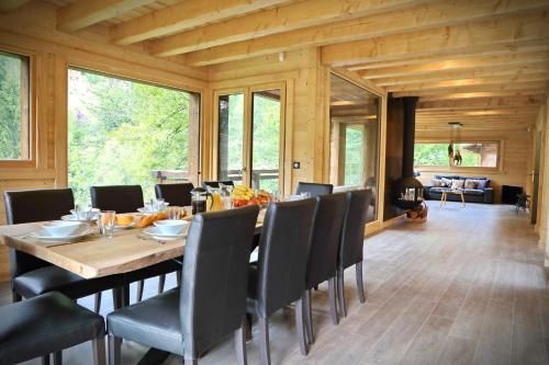 une salle à manger avec une grande table et des chaises en bois dans l'établissement Forest Lodge - Modern Luxury Nestled in the Pines, à Montriond