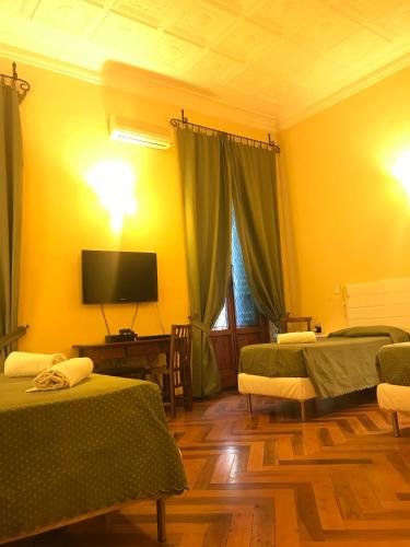 a room with two beds and a tv on the wall at Hotel Giglio in Florence