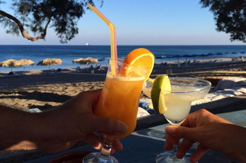 a person holding a drink in front of the beach at Petroto Villas in Kiotari
