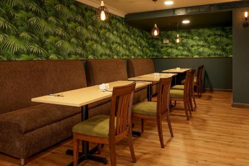 a restaurant with tables and chairs and a green wall at Shahzan Hotel Kuantan, Trademark Collection by Wyndham in Kuantan