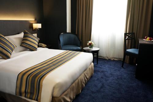 a hotel room with a bed and a chair at Shahzan Hotel Kuantan, Trademark Collection by Wyndham in Kuantan