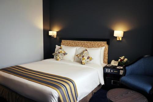 a hotel room with a bed and a blue chair at Shahzan Hotel Kuantan, Trademark Collection by Wyndham in Kuantan