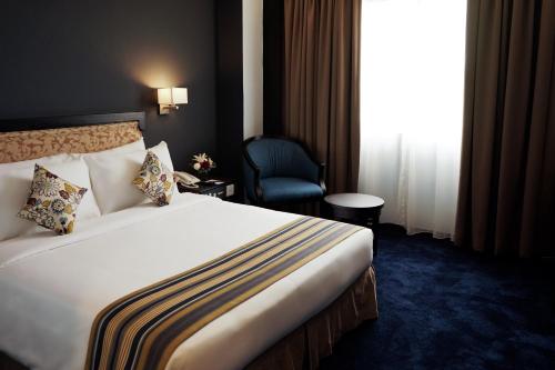 a hotel room with a large bed and a chair at Shahzan Hotel Kuantan, Trademark Collection by Wyndham in Kuantan