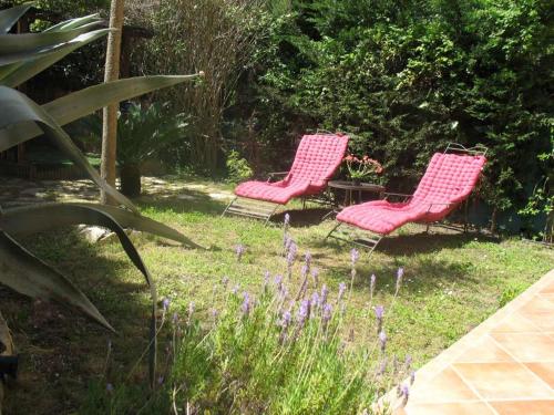 2 chaises roses assises dans une cour fleurie dans l'établissement Appartement de charme wi-fi ,clim, garage jardin privés, piscine environnement arboré, à Cannes