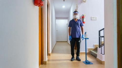 a man wearing a mask standing in a hallway with a mop at Kay's Riverview Resort - Near Baga Beach in Baga