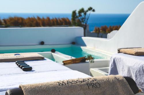 two massage beds sitting next to a swimming pool at Santolia Art Suites in Oia