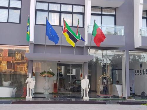 un edificio con cuatro banderas delante de él en Indico Executivo Hotel, en Cidade de Nacala