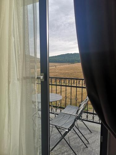 a balcony with a chair and a table and a field at Adonis 201 in Zlatibor