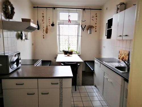 cocina con armarios blancos y encimera negra en Ferienwohnung HARZgeNUSS, en Wernigerode