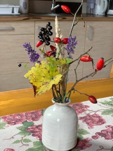 a white vase with flowers in it on a table at Pécsely apartman in Pécsely