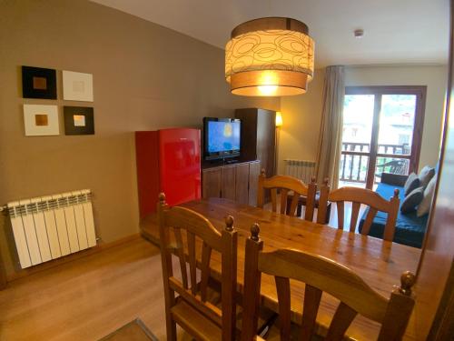a dining room with a wooden table and a television at Apartamentos Los Lagos in Benasque