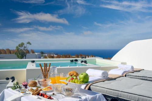 a table with a bowl of fruit on a balcony at Santolia Art Suites in Oia