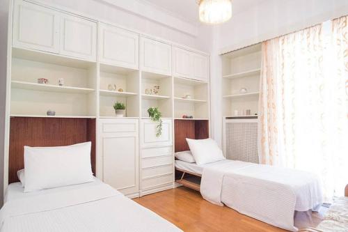 dwa łóżka w pokoju z białymi szafkami i oknem w obiekcie Spacious and Luxurious Apartment in Athens Center w Atenach